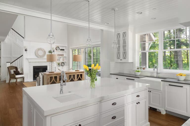 Beautiful kitchen interior with island, two sinks, hardwood floors, and view of living room with vaulted ceilings